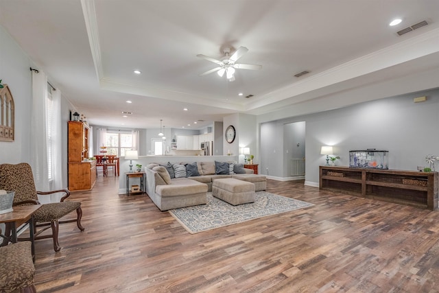 living room featuring visible vents, a raised ceiling, and wood finished floors