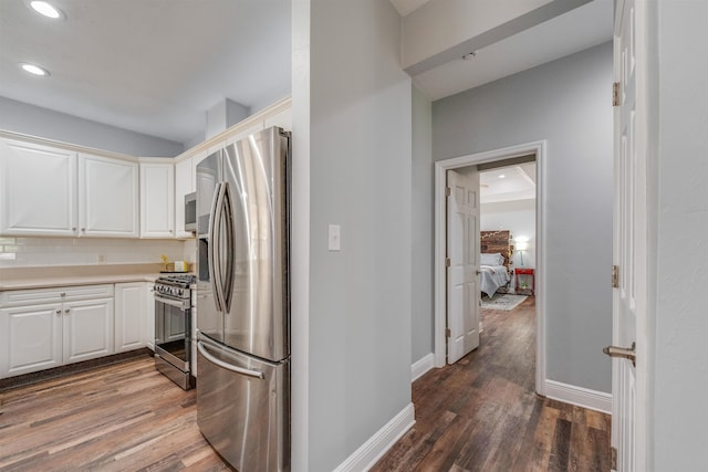 kitchen featuring white cabinetry, stainless steel appliances, baseboards, and wood finished floors