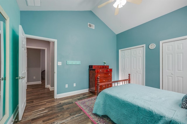 bedroom with visible vents, two closets, lofted ceiling, and wood finished floors