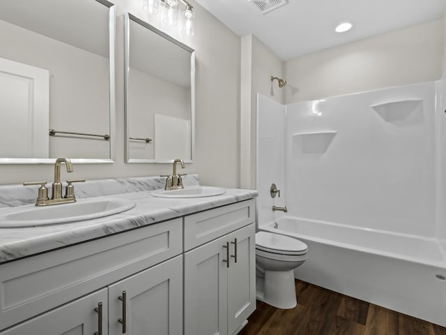 bathroom with double vanity, tub / shower combination, a sink, and wood finished floors