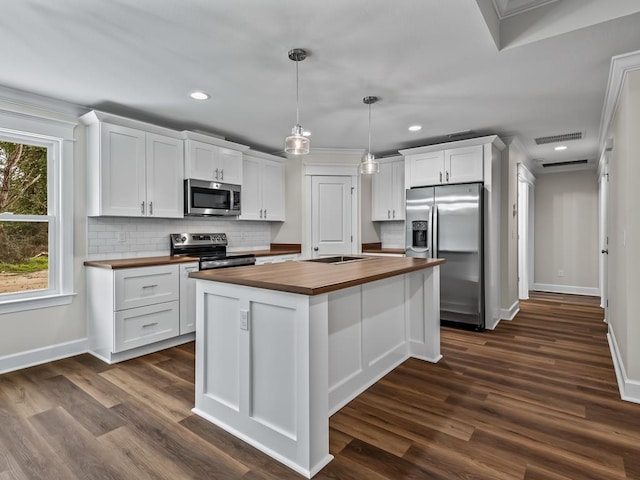 kitchen featuring butcher block countertops, a center island, appliances with stainless steel finishes, and white cabinetry