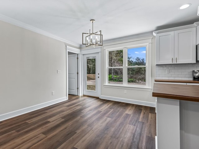 unfurnished dining area with baseboards, ornamental molding, dark wood-style flooring, a notable chandelier, and recessed lighting