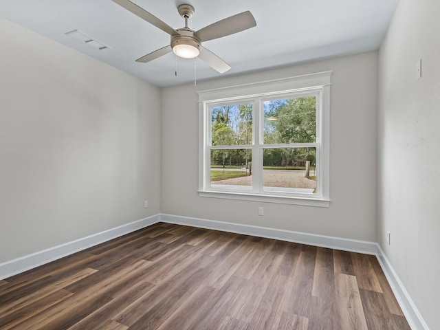 spare room with dark wood-style flooring, visible vents, ceiling fan, and baseboards