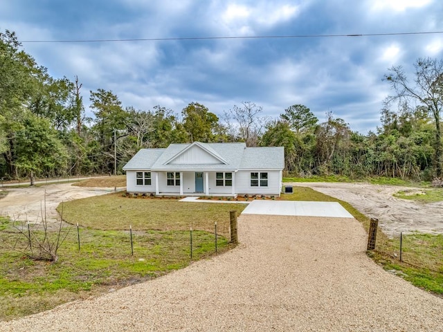 view of front of home featuring driveway, covered porch, fence, and a front lawn