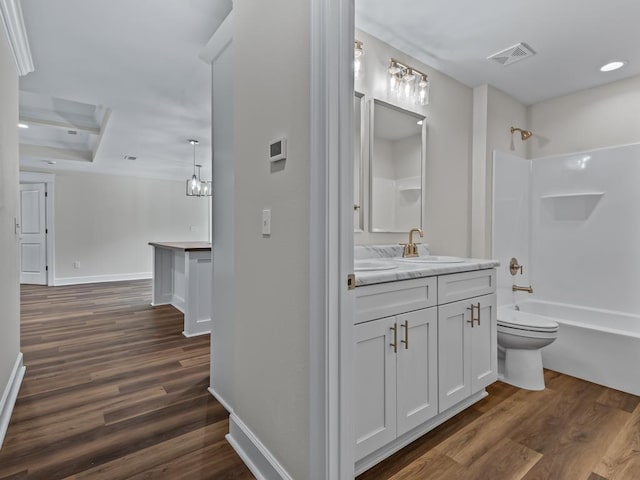 bathroom with visible vents, toilet, wood finished floors,  shower combination, and vanity