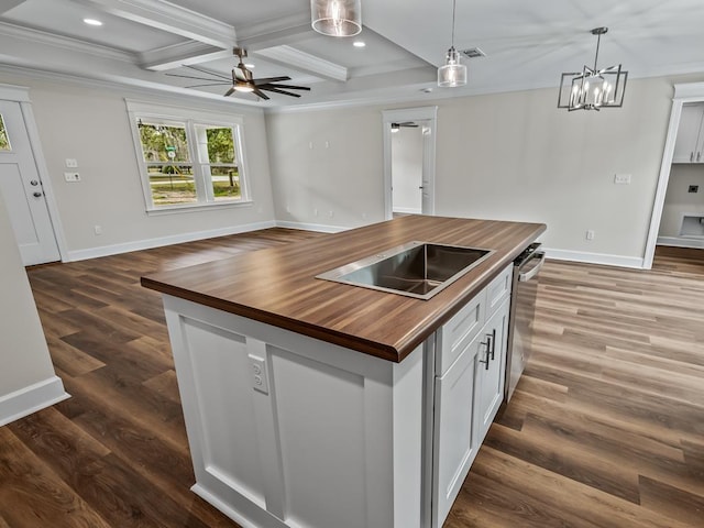 kitchen with white cabinets, butcher block countertops, open floor plan, and a center island with sink