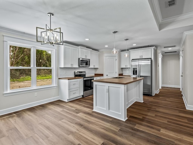 kitchen with white cabinets, stainless steel appliances, wooden counters, and decorative light fixtures