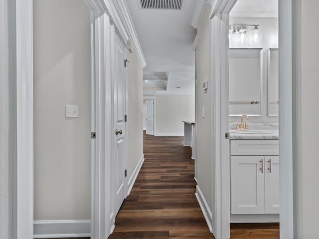 hallway with dark wood-style floors, visible vents, and baseboards