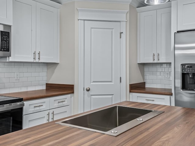 kitchen with butcher block countertops and white cabinetry