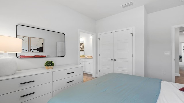 bedroom with ensuite bathroom, a closet, and light hardwood / wood-style floors