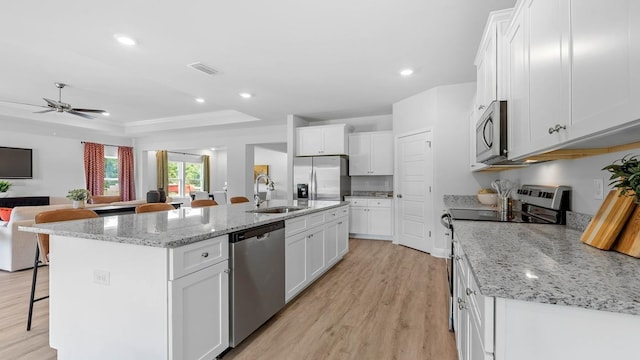 kitchen featuring white cabinets, appliances with stainless steel finishes, an island with sink, and sink