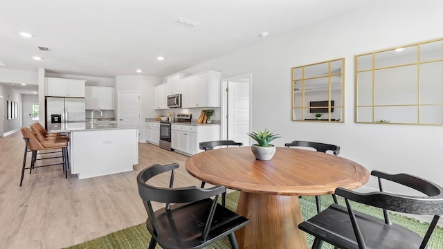 dining space with light hardwood / wood-style floors and sink