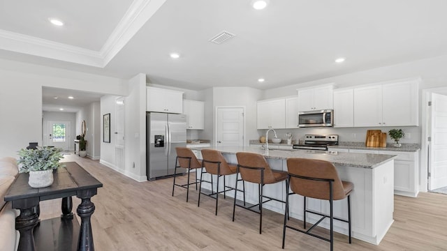 kitchen featuring white cabinets, a kitchen breakfast bar, light stone counters, and stainless steel appliances