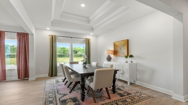 dining room featuring a tray ceiling, crown molding, and light wood-type flooring