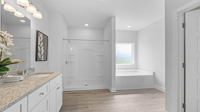 bathroom with plus walk in shower, vanity, and hardwood / wood-style flooring