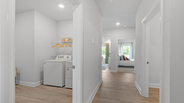 hall with washer and clothes dryer and light hardwood / wood-style flooring