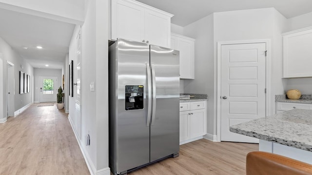 kitchen featuring white cabinetry, stainless steel fridge with ice dispenser, light stone counters, and light wood-type flooring