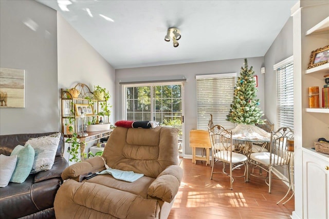 living room with plenty of natural light, vaulted ceiling, and light wood-type flooring