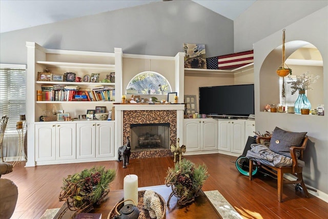 living room with a tile fireplace, hardwood / wood-style floors, and lofted ceiling