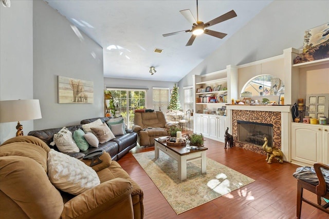 living room featuring high vaulted ceiling, ceiling fan, dark wood-type flooring, and a tiled fireplace