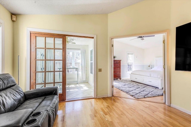 entryway with lofted ceiling, light wood finished floors, a textured ceiling, and baseboards