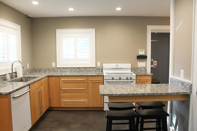 kitchen featuring light stone countertops, dishwasher, sink, kitchen peninsula, and a breakfast bar area