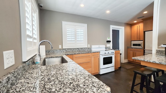 kitchen with light stone countertops, sink, white appliances, and kitchen peninsula