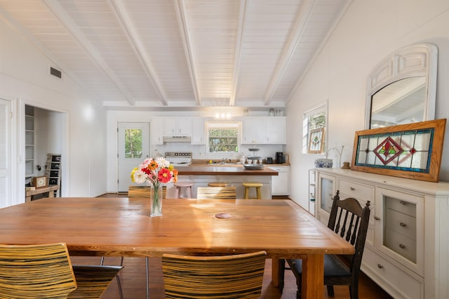 dining area with vaulted ceiling with beams