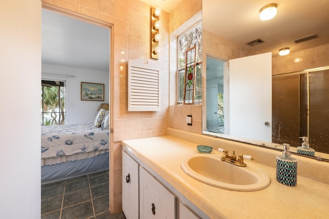 bathroom featuring a shower with shower door, tile walls, and vanity