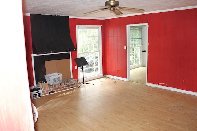 living room with baseboards, ceiling fan, wood finished floors, crown molding, and a textured ceiling