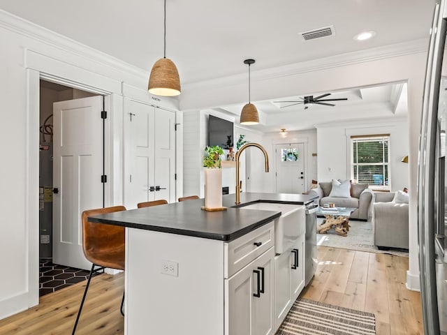 kitchen featuring white cabinets, sink, ceiling fan, decorative light fixtures, and a breakfast bar area