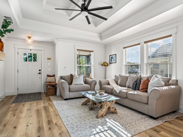 living room with a raised ceiling, ceiling fan, light hardwood / wood-style flooring, and ornamental molding