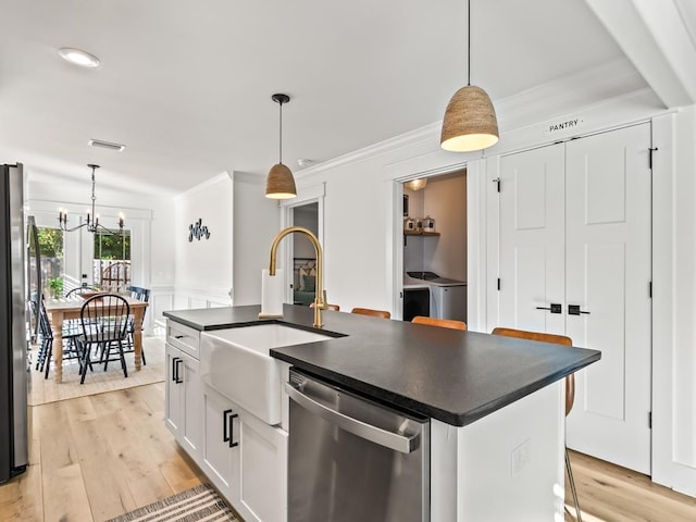 kitchen featuring a center island with sink, white cabinets, decorative light fixtures, and appliances with stainless steel finishes