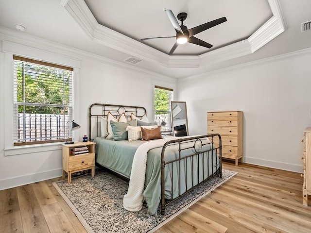 bedroom with multiple windows, a tray ceiling, and ceiling fan