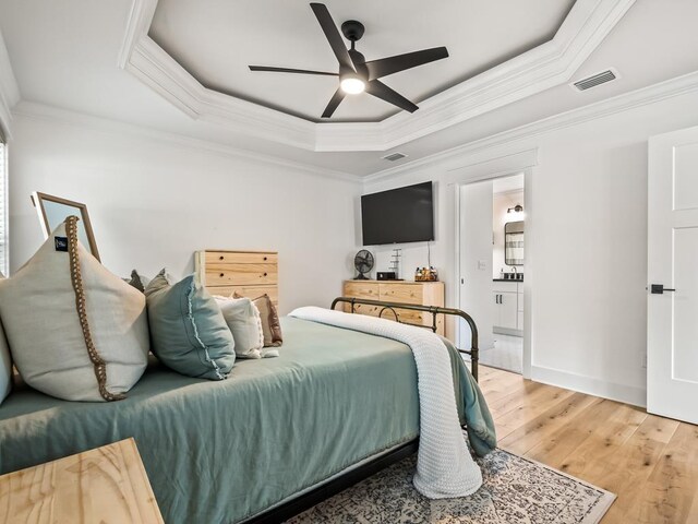 bedroom with hardwood / wood-style floors, a tray ceiling, ceiling fan, and crown molding