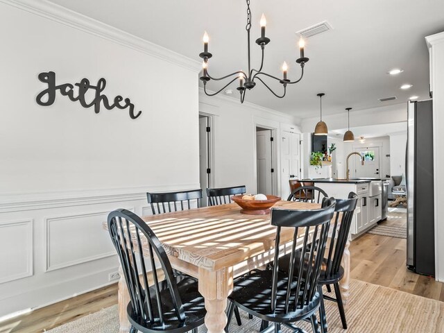 dining room with light hardwood / wood-style flooring, a chandelier, and ornamental molding