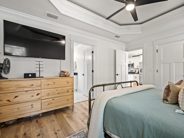 bedroom featuring crown molding, light hardwood / wood-style flooring, ceiling fan, a tray ceiling, and stainless steel fridge with ice dispenser