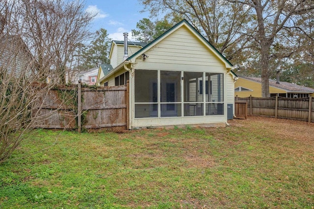 rear view of property with a lawn, a fenced backyard, and a sunroom