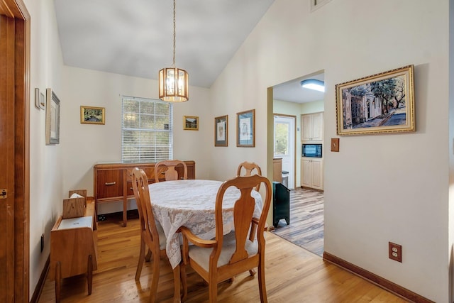 dining area featuring baseboards, lofted ceiling, and light wood-style floors