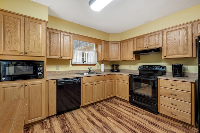 kitchen with under cabinet range hood, light brown cabinets, black appliances, and a sink