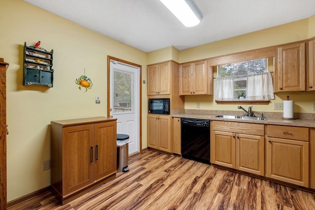 kitchen with baseboards, light wood-type flooring, light countertops, black appliances, and a sink