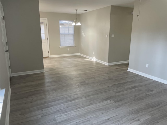 empty room featuring an inviting chandelier and dark wood-type flooring