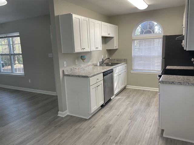 kitchen featuring sink, light hardwood / wood-style flooring, appliances with stainless steel finishes, light stone countertops, and white cabinets