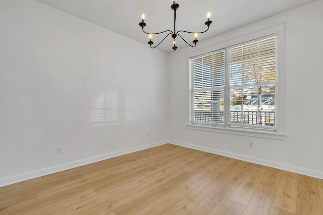 empty room featuring light hardwood / wood-style floors and an inviting chandelier