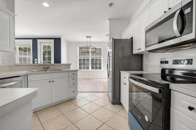 kitchen featuring white cabinetry, sink, stainless steel appliances, decorative light fixtures, and light tile patterned flooring