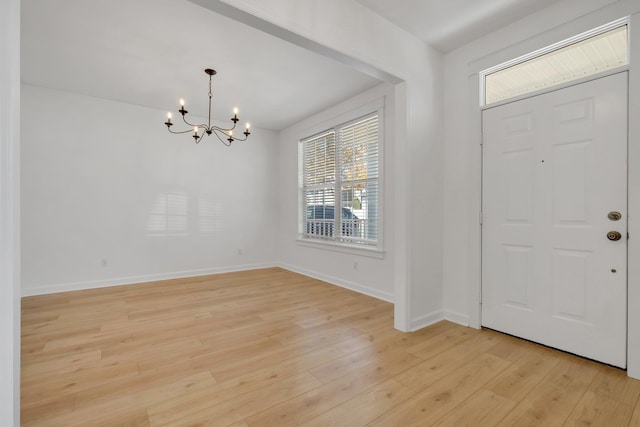 foyer with a notable chandelier, a healthy amount of sunlight, and light wood-type flooring