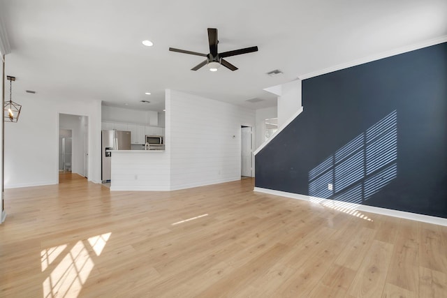 unfurnished living room featuring light hardwood / wood-style flooring, ceiling fan, and crown molding