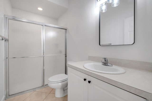 bathroom with toilet, vanity, tile patterned floors, and a shower with shower door