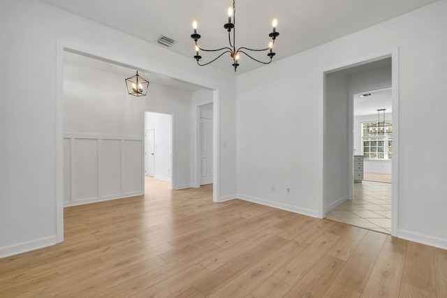 unfurnished dining area featuring a chandelier and light wood-type flooring