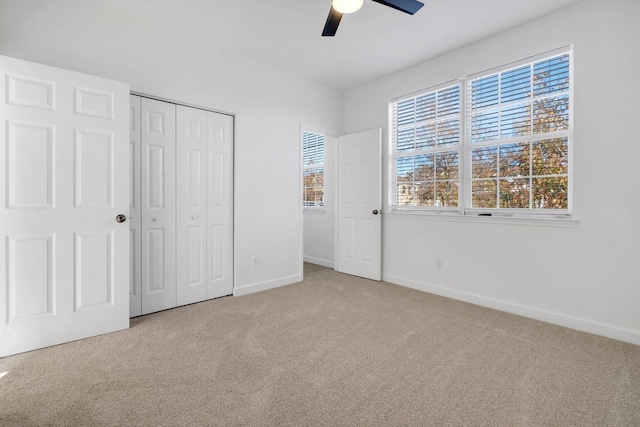 unfurnished bedroom featuring ceiling fan, a closet, and light colored carpet